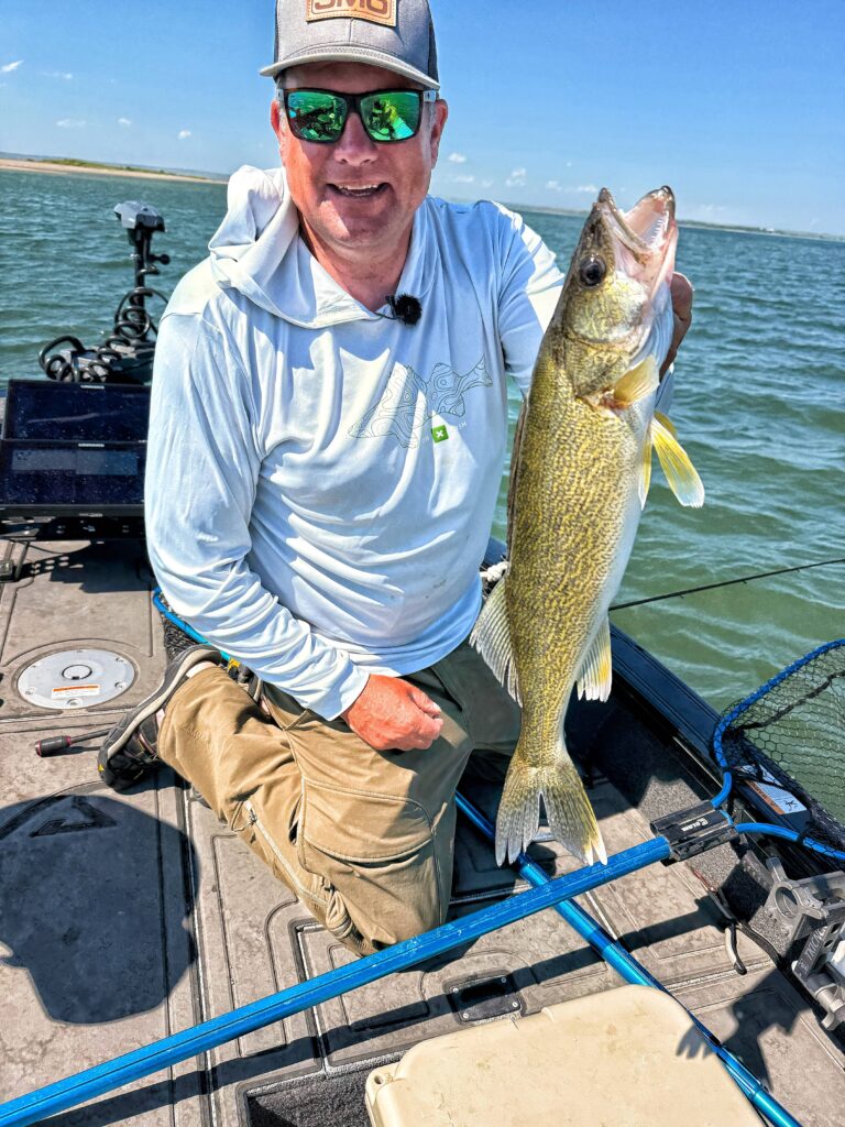 Bottom Bouncer and Slow Death Rig with a Half Crawler | A smiling fisherman kneels on a boat, proudly holding a large walleye he just caught.