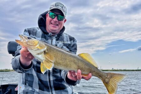 Angler holding a large fall walleye caught during a cool-weather fishing trip.